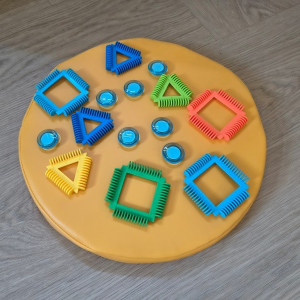 kolorowe figury geometryczne ułożone na zółtej, okrągłej podstawie